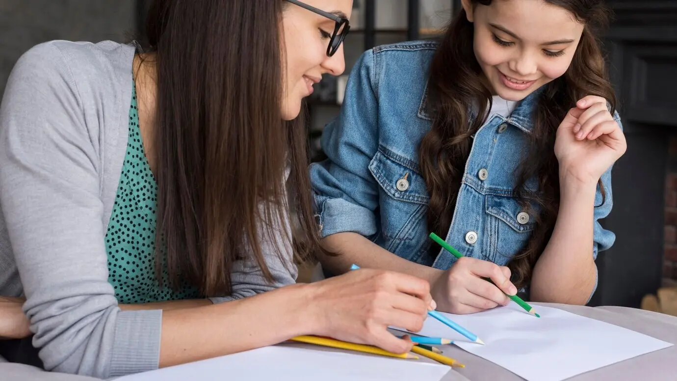Una madre enseña a una niña a dibujar.